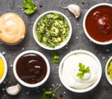 Set of sauces - ketchup, mayonnaise, mustard soy sauce, bbq sauce, pesto, chimichurri, mustard grains and pomegranate sauce on dark stone background.